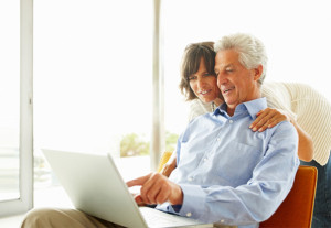 a man and woman sitting on a couch using a laptop