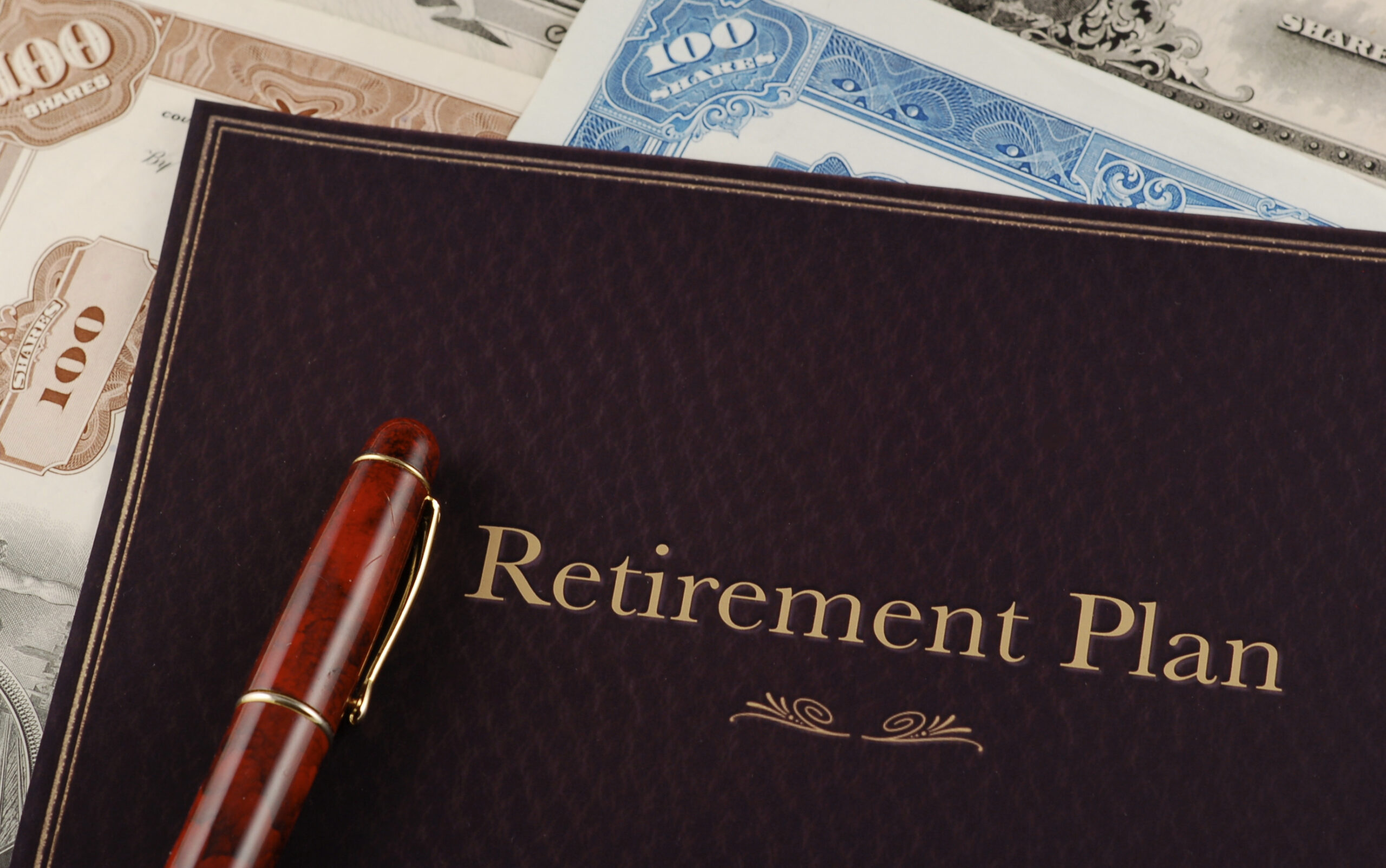 a pen and a book with a retirement plan on it