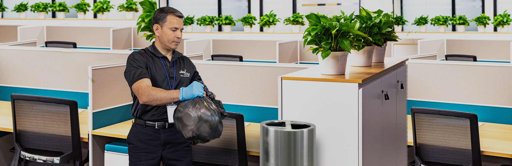 a man in a black shirt and blue gloves is standing in an office
