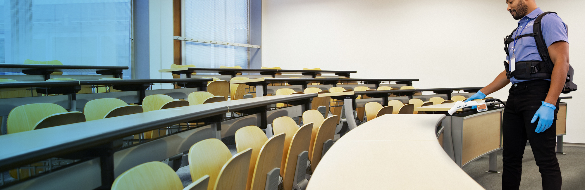 a man in a blue shirt and black pants cleaning a classroom