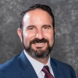 a man in a suit and tie smiling Logan Hakes' professional headshot