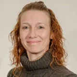 a woman with red hair and a gray sweater Misty Etheridge of Jani-King professional headshot.