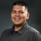 a man in a black shirt smiles at the camera Rafael Rudea's professional headshot