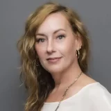a woman with long blonde hair and a white top Trinity Lucketta's professional headshot